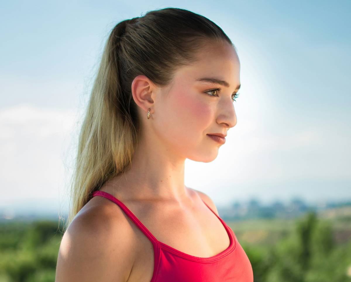 Woman in workout clothes demonstrating a breathable gym hair idea with a loose braid